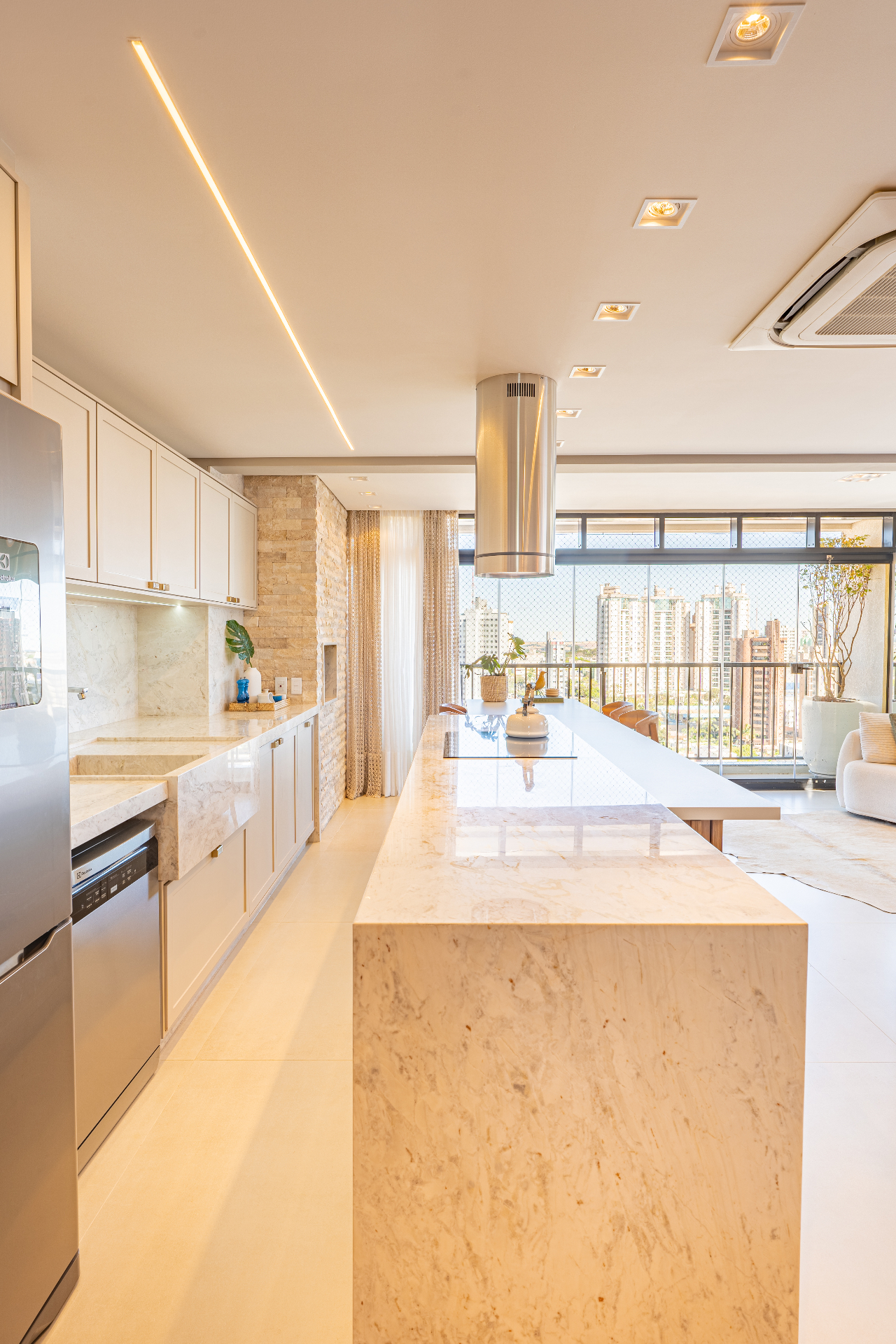 Cozinha em mármore com ilha, coifa inox e vista da cidade