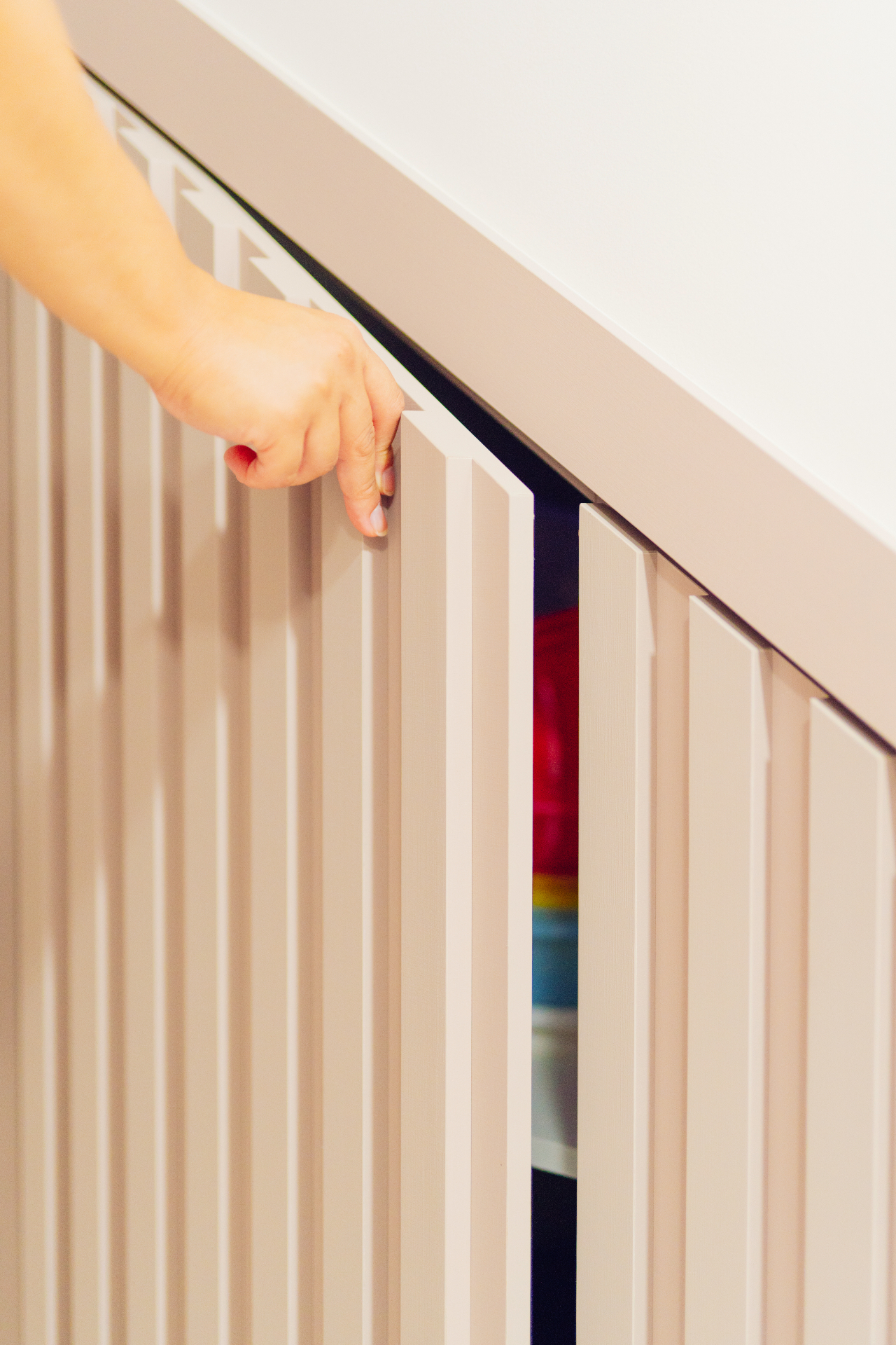 Mão abrindo porta ripada de armário planejado