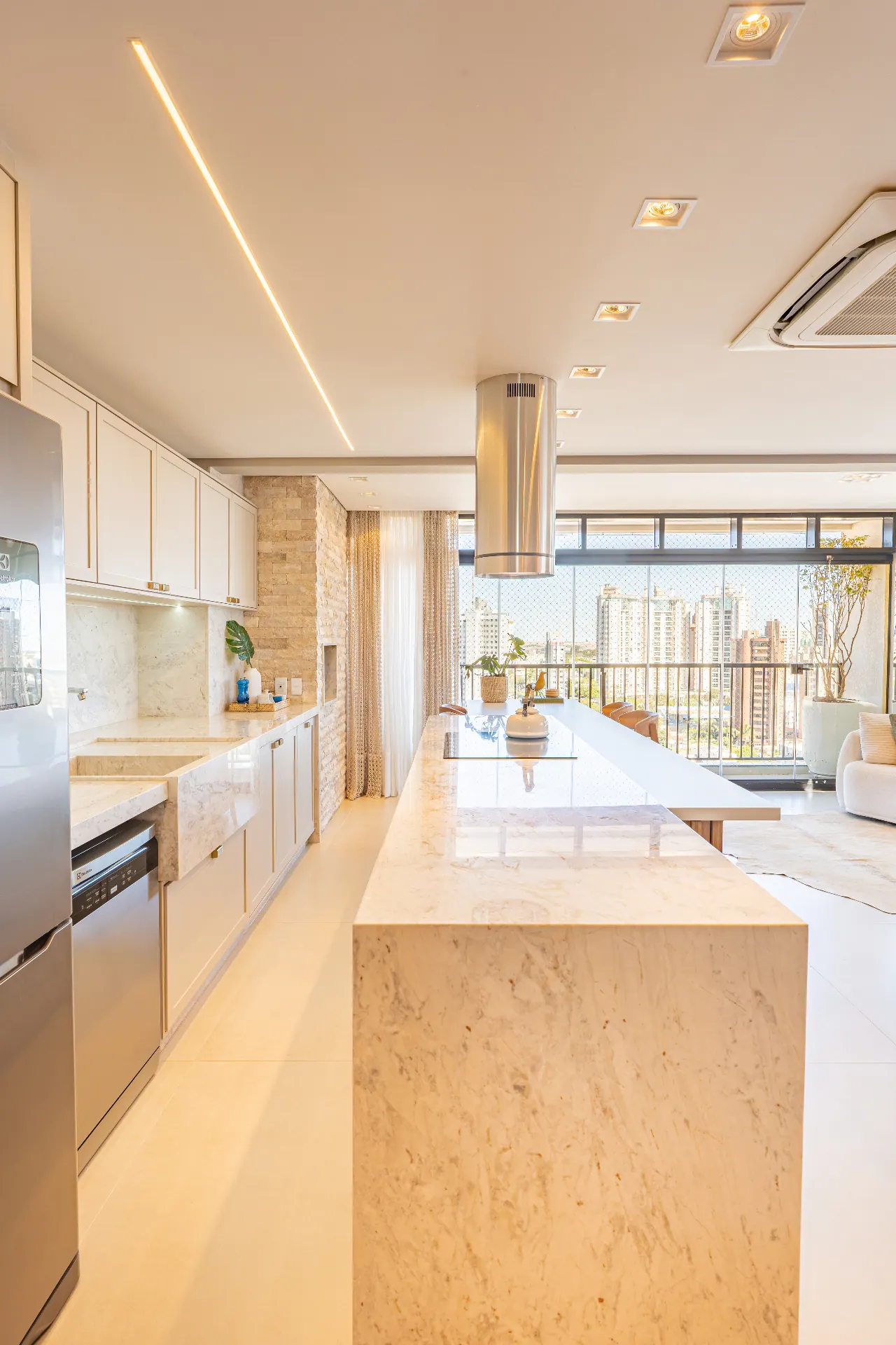 Cozinha em mármore com ilha, coifa inox e vista da cidade