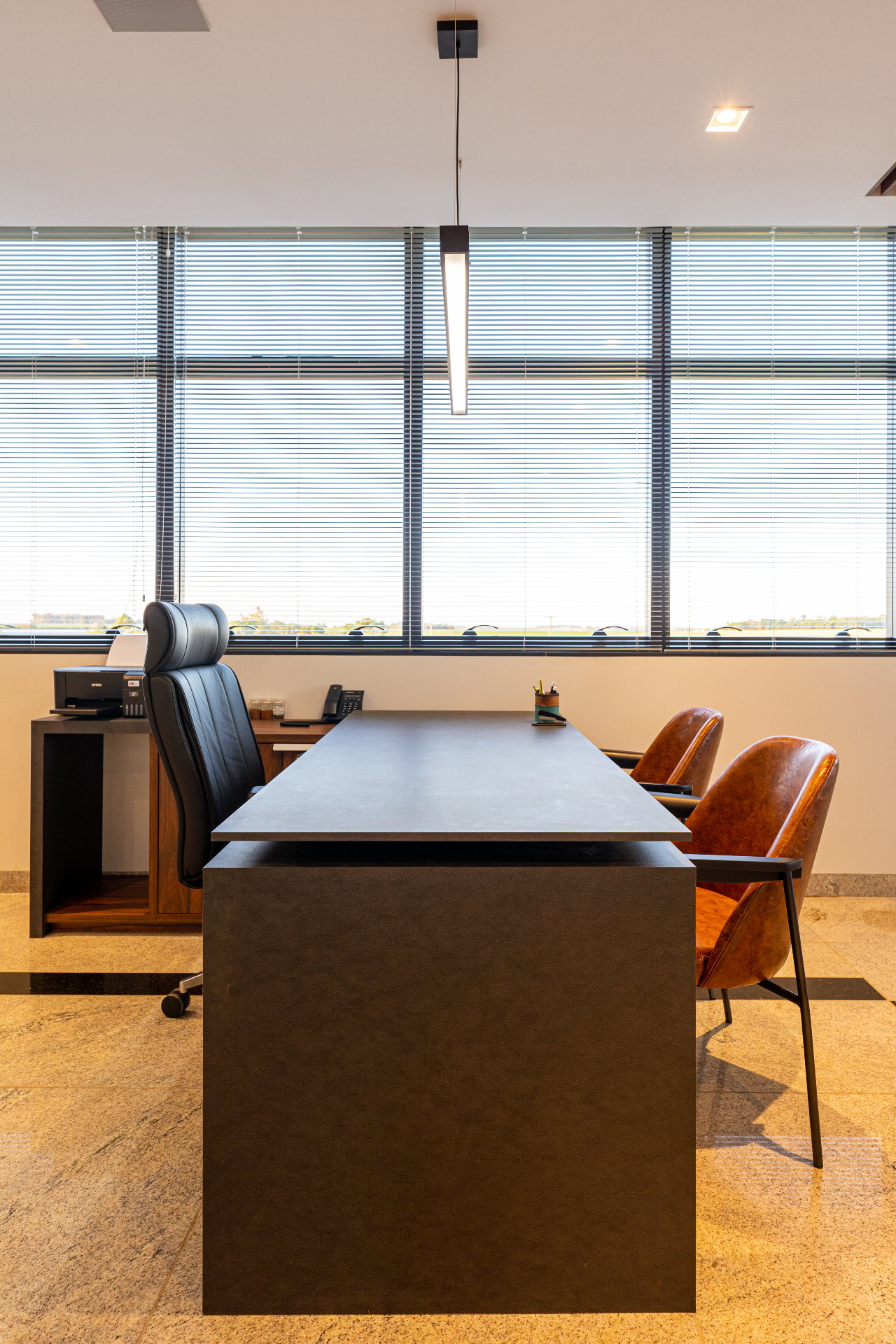 Escritório com mesa escura e cadeiras em couro