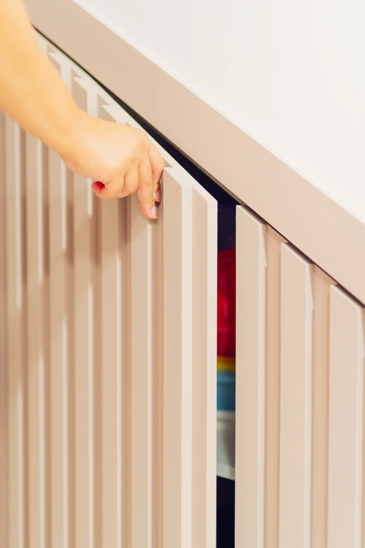 Mão abrindo porta ripada de armário planejado